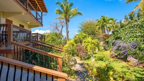 Un jardin luxuriant avec un escalier en bois menant à un balcon.