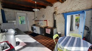 Cocina compacta con electrodomésticos básicos, un pequeño comedor y vistas al exterior.