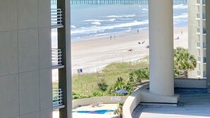 A view from a balcony overlooking a beach with a pier in the distance. - Royale Palms 602H Oceanview Studio in Kingston (Myrtle Beach)