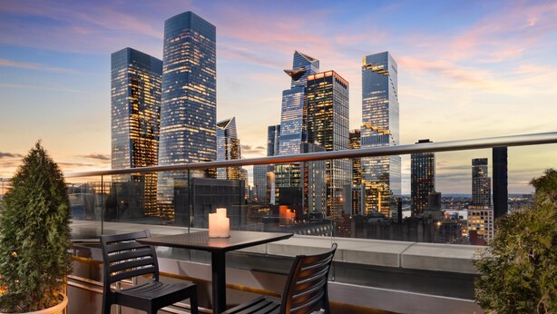 A rooftop terrace with a city skyline view, modern furniture, and a potted plant. - Doubletree by Hilton New York Times Square South (New York)