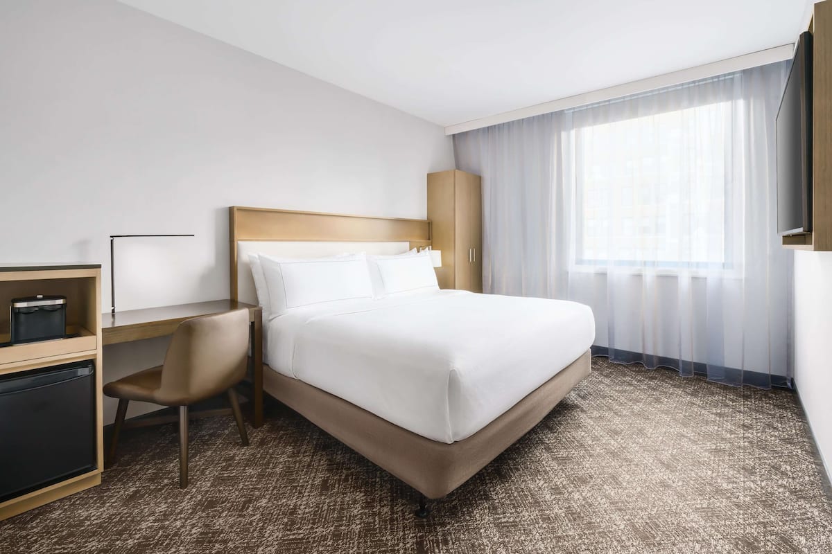 Ein Hotelzimmer mit einem Bett, einem Schreibtisch, einem Stuhl und einem Kleiderschrank.