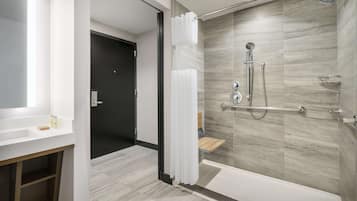 A modern bathroom with a glass-enclosed shower, a wooden vanity, and a mirror.