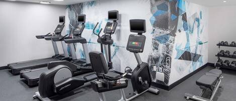 A modern gym with treadmills, elliptical machines, and weight benches.