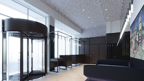 A modern lobby with a revolving door, seating area, and a large abstract painting on the wall. - Doubletree by Hilton New York Times Square South (New York)