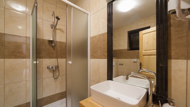 A modern bathroom with a glass-enclosed shower, a wooden vanity with a white sink, and a mirror. - House Maka (Plitvicka Jezera)