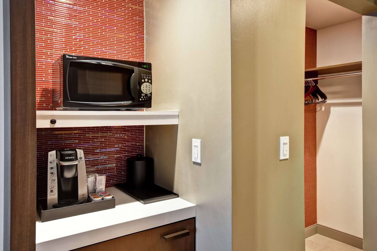 A kitchenette with a microwave, coffee maker, and a small countertop.