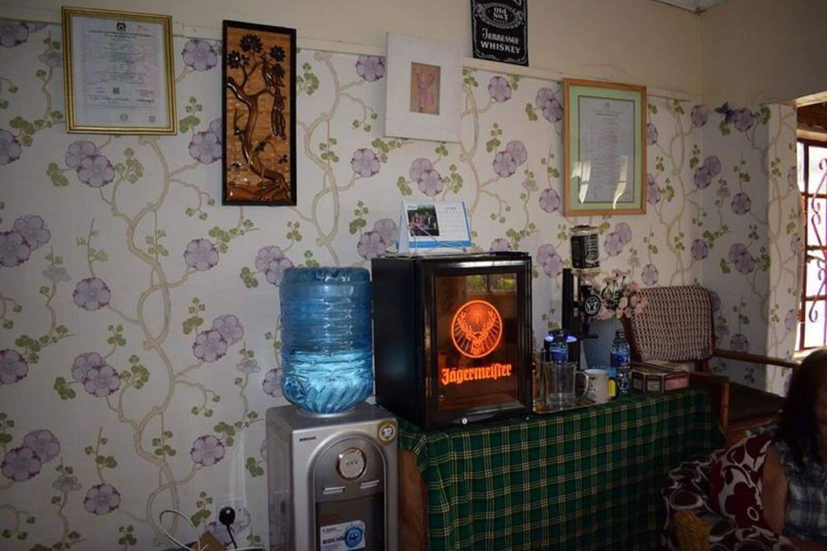Ett rum med en vattenautomat, en tv som visar en logotyp, ett bord med en grön duk och blommig tapet.