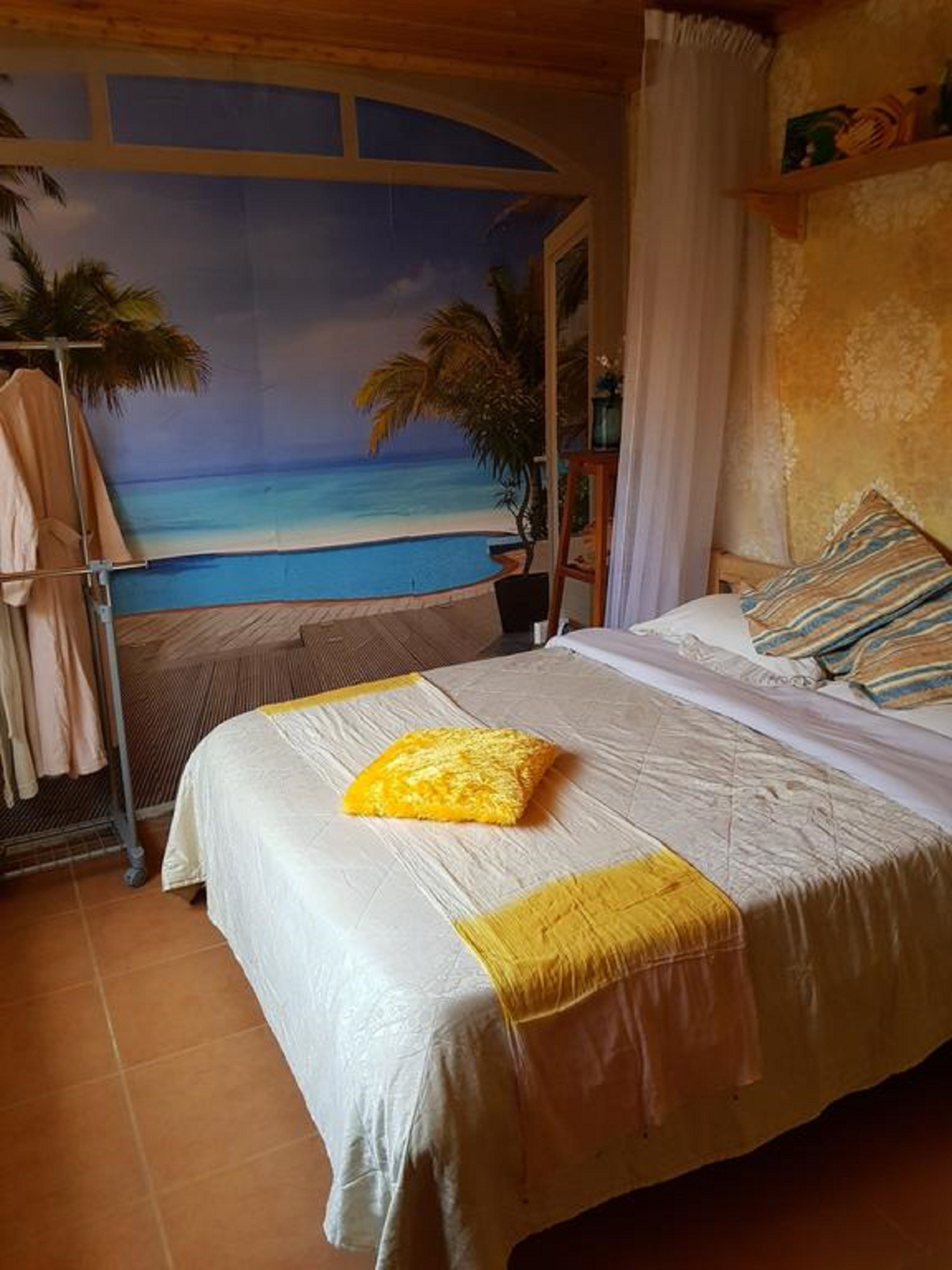 Une chambre avec un lit, une vue sur la plage et une étagère avec quelques objets.