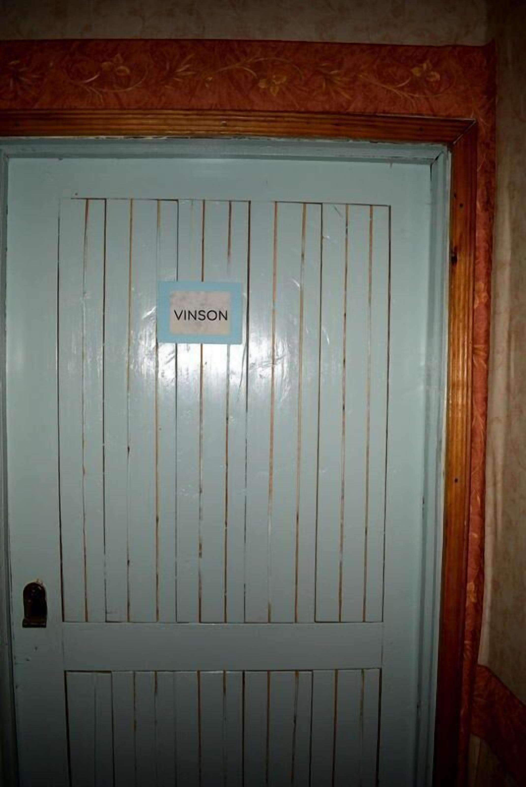 Una puerta con listones verticales y un letrero que dice 'VINSON'.