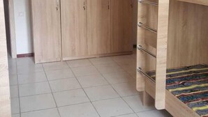 Een slaapkamer met een stapelbed, een kledingkast en een betegelde vloer.