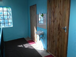 A bathroom with a wooden door, a window, and a sink. - Karugia House (Murang'a)