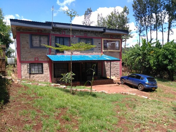 A two-story house with a blue roof and a car parked in front. - Karugia House (Murang'a)