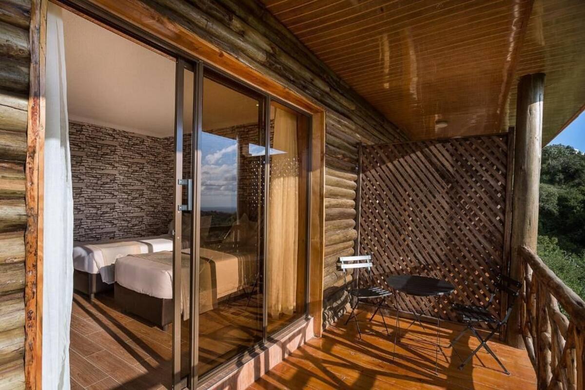 Una cabaña de madera con balcón, una cama y una mesa.