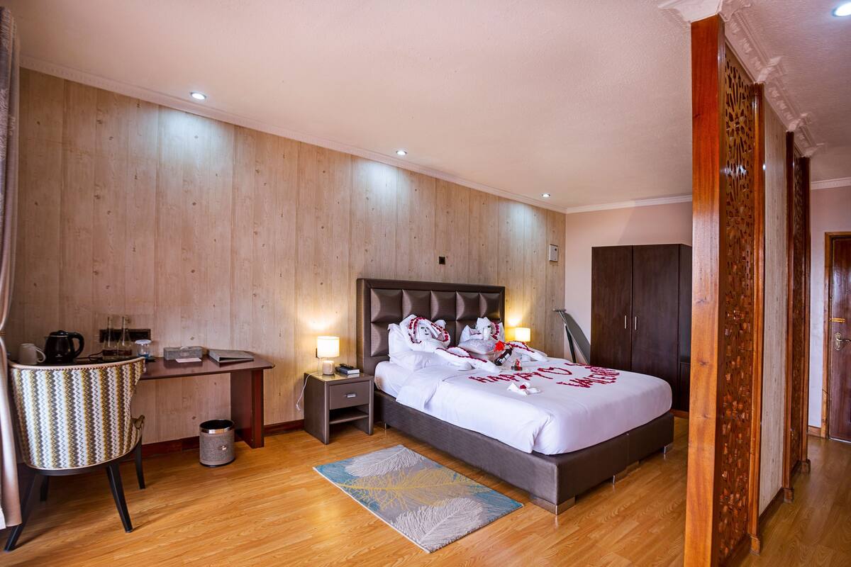 Una habitación de hotel con cama, mesitas de noche, escritorio, silla y armario.