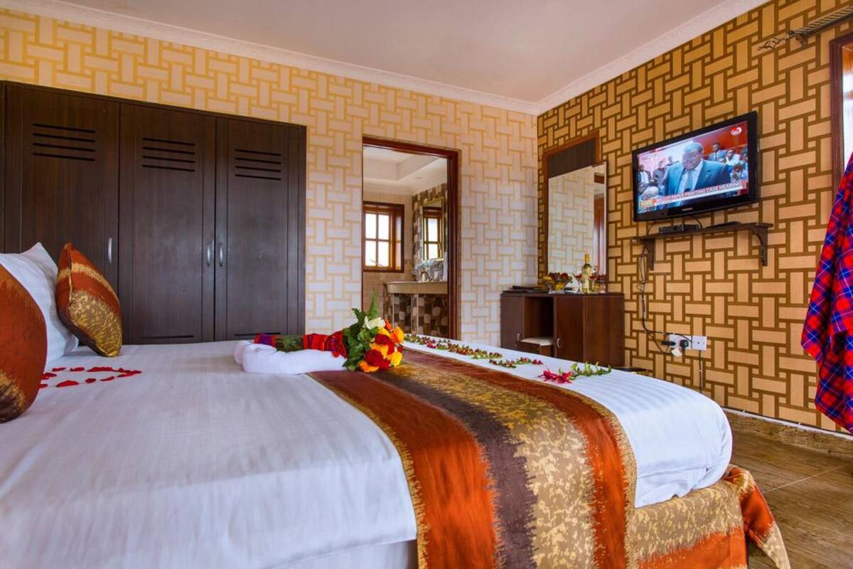 Una habitación de hotel con dos camas, televisión, armario y espejo.