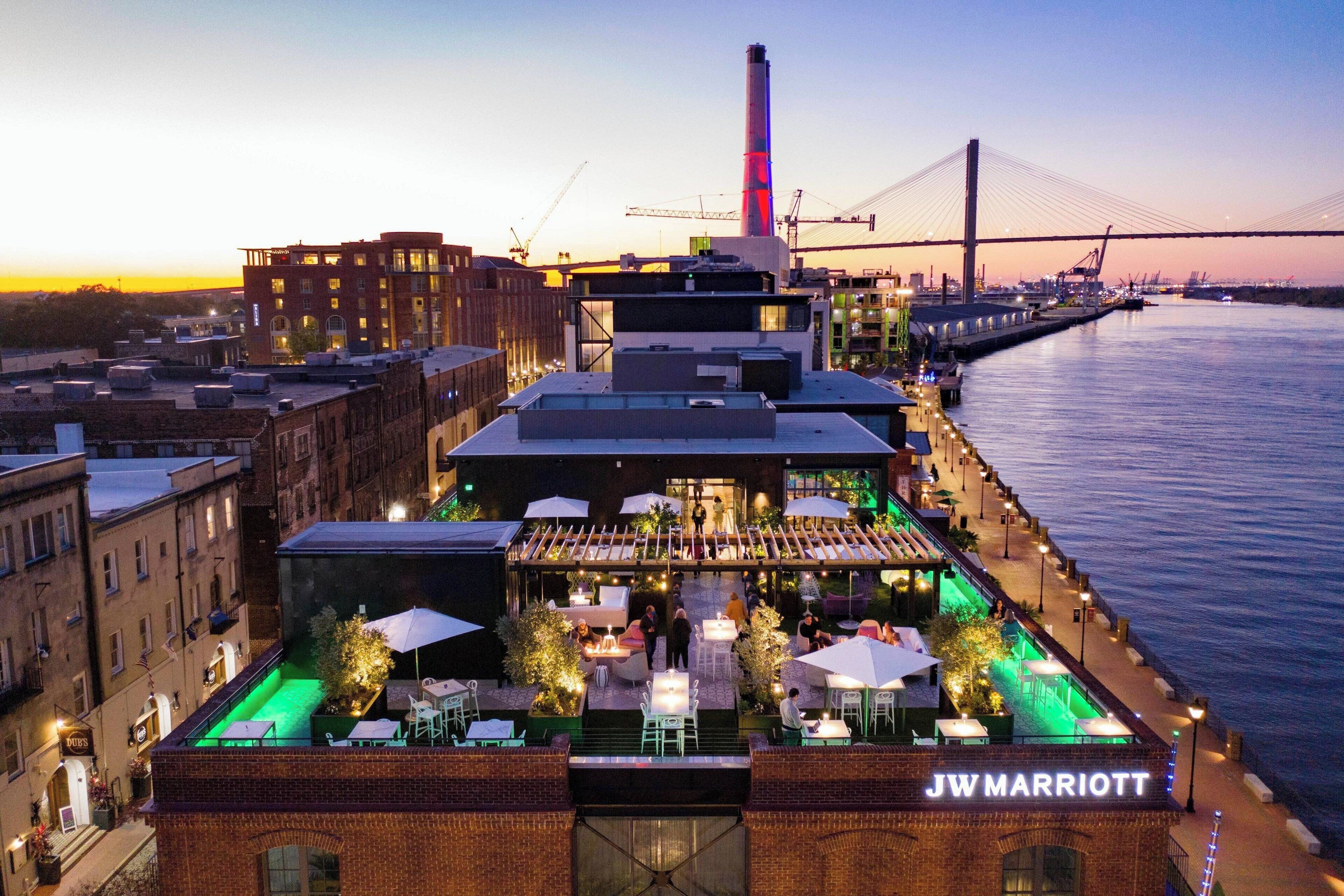 Tagterrasse på JW Marriott med udendørs siddepladser og udsigt over floden og broen.