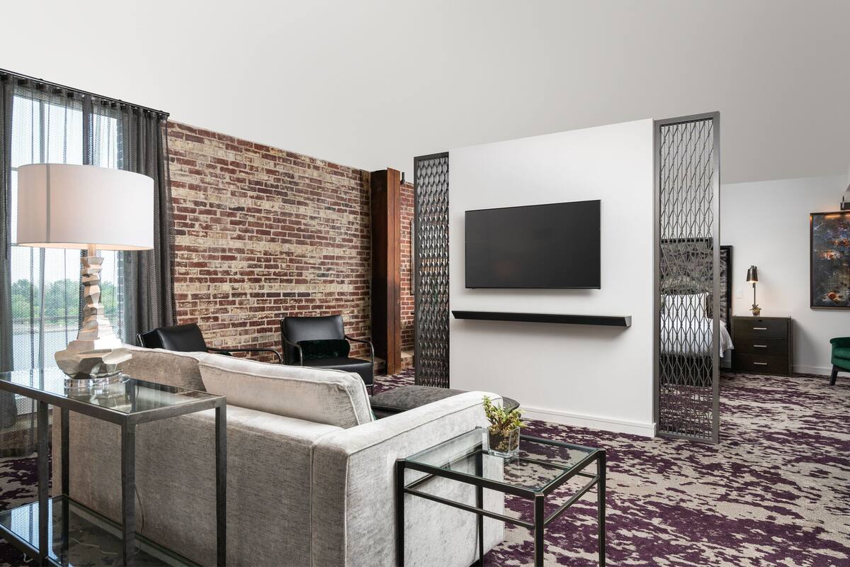 A modern living room with a brick wall, a sofa, a coffee table, and a TV mounted on the wall.