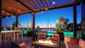 An outdoor patio with a fire feature, seating, and a view of a cityscape at dusk. - JW Marriott Savannah Plant Riverside District (Savannah)