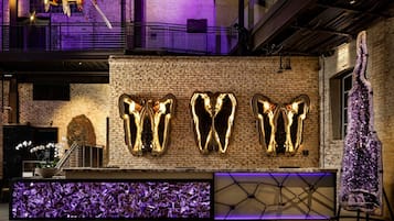 A reception area with a brick wall, a large decorative sculpture, and a purple-lit display.