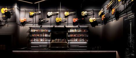 A bar area with multiple guitars displayed on the wall and a well-stocked liquor shelf.
