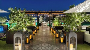 A rooftop terrace with a central seating area, surrounded by planters and lanterns, under a pergola. - JW Marriott Savannah Plant Riverside District (Savannah)