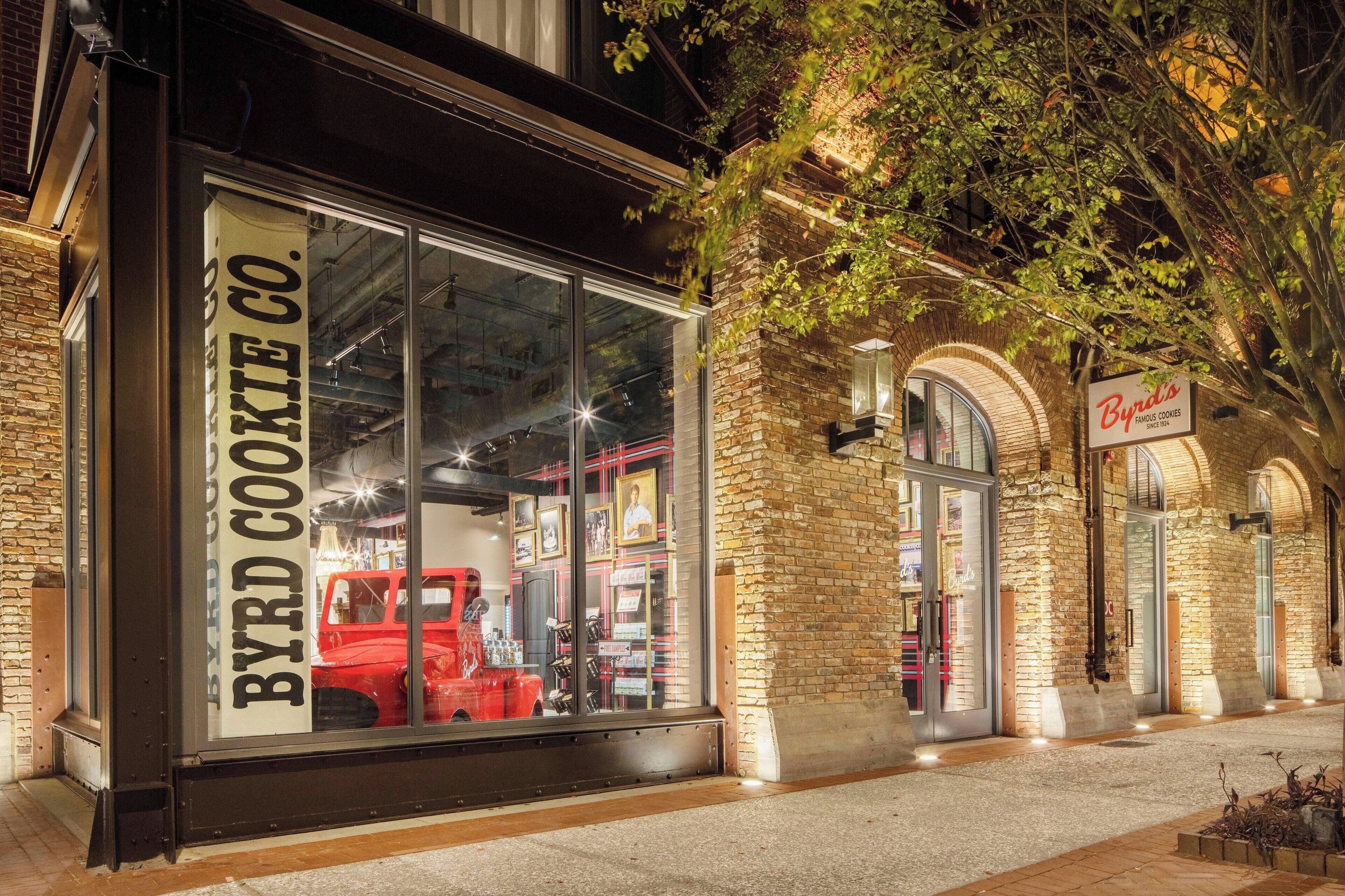 Une devanture de magasin avec une grande vitrine où est exposée une voiture rouge d’époque et une enseigne indiquant « BYRD COOKIE CO. »