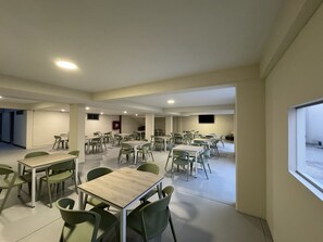 A spacious dining area with multiple tables and chairs, a flat-screen TV mounted on the wall, and a window providing natural light. - 44 Vip Hotel (Lima)
