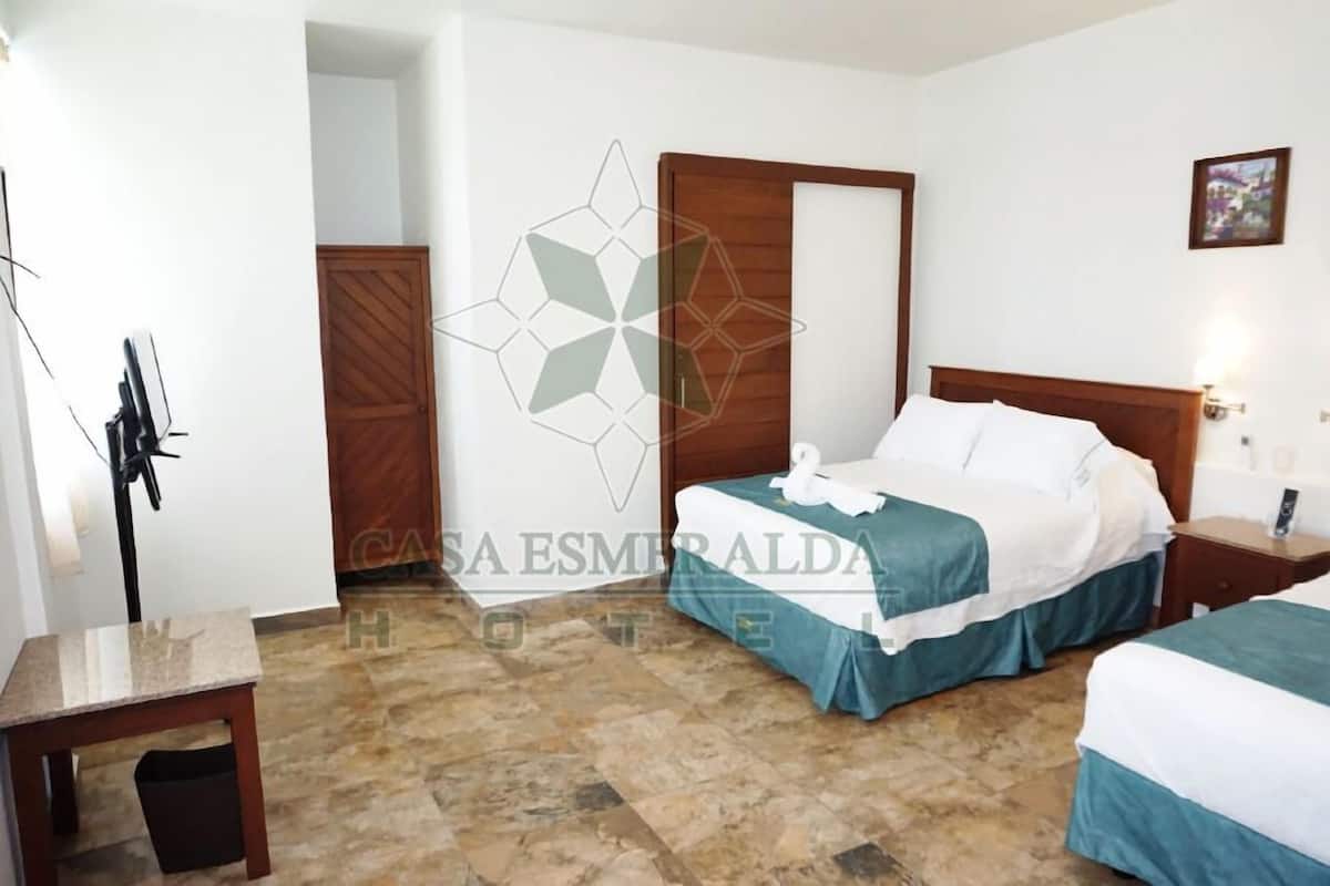 A hotel room with a bed, bedside tables, a desk, and a trash bin.