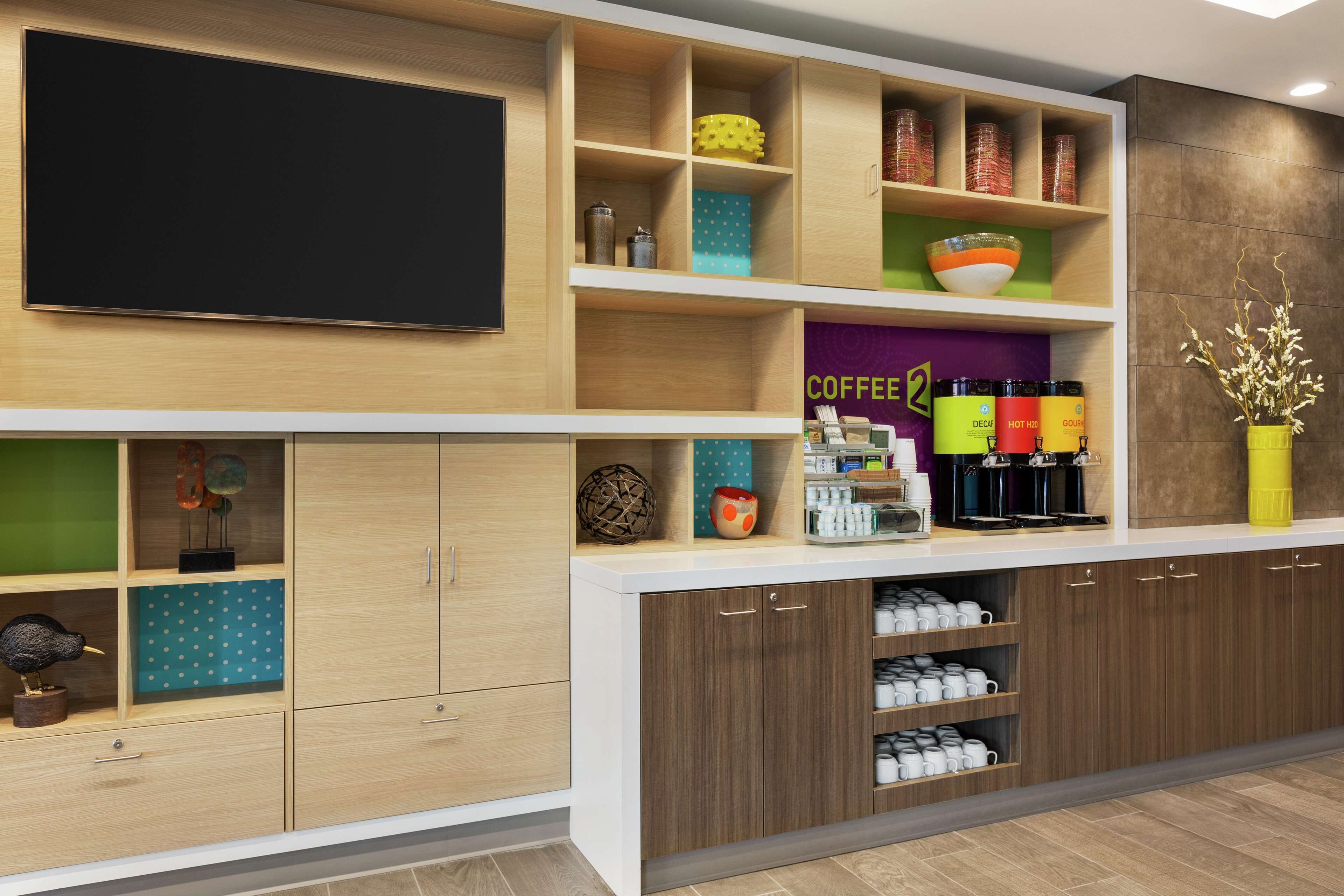 Una cocina moderna con armarios de madera, una estación de café integrada y un televisor de pantalla plana.
