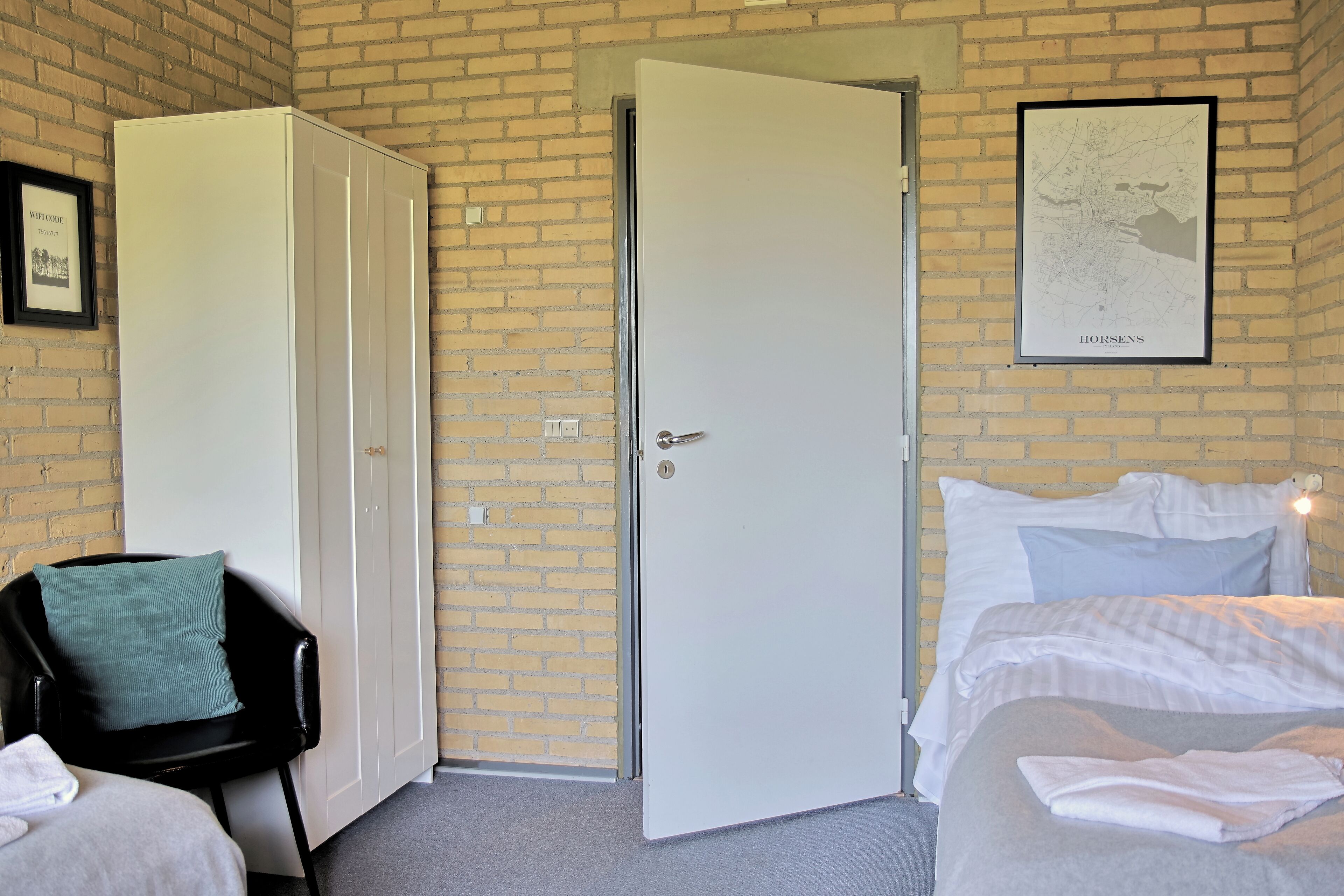 A room with a bed, a chair, a wardrobe, and a map on the wall.