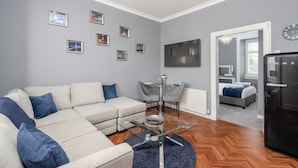 Una sala moderna con un sofá, una mesa de centro de vidrio y un comedor con sillas.