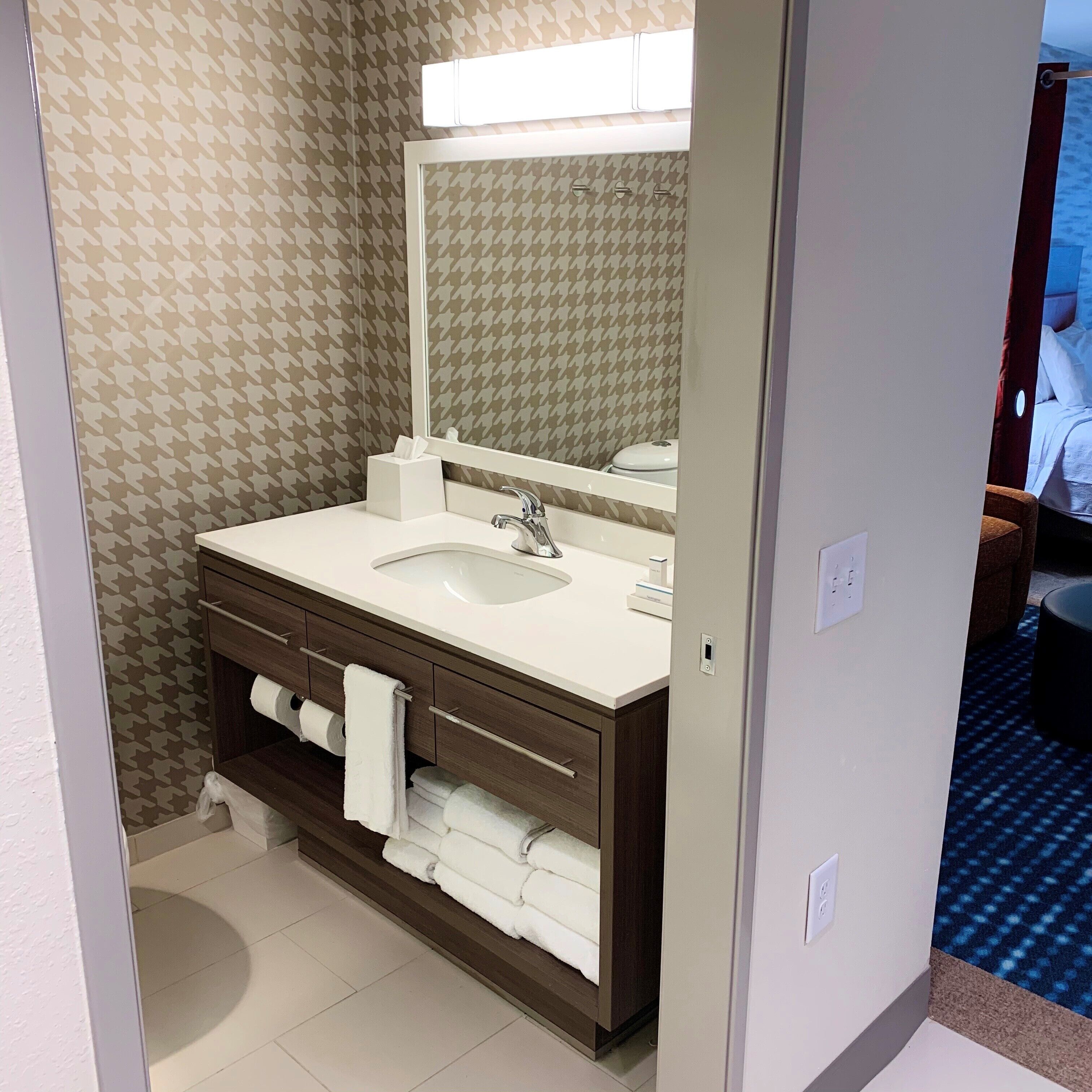A bathroom with a white sink, a mirror, and a towel rack.