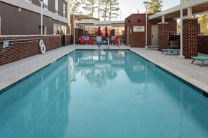 Une piscine équipée d’un poste de surveillance pour sauveteur, d’un panneau indiquant la profondeur de l’eau et d’un espace abrité avec des chaises.