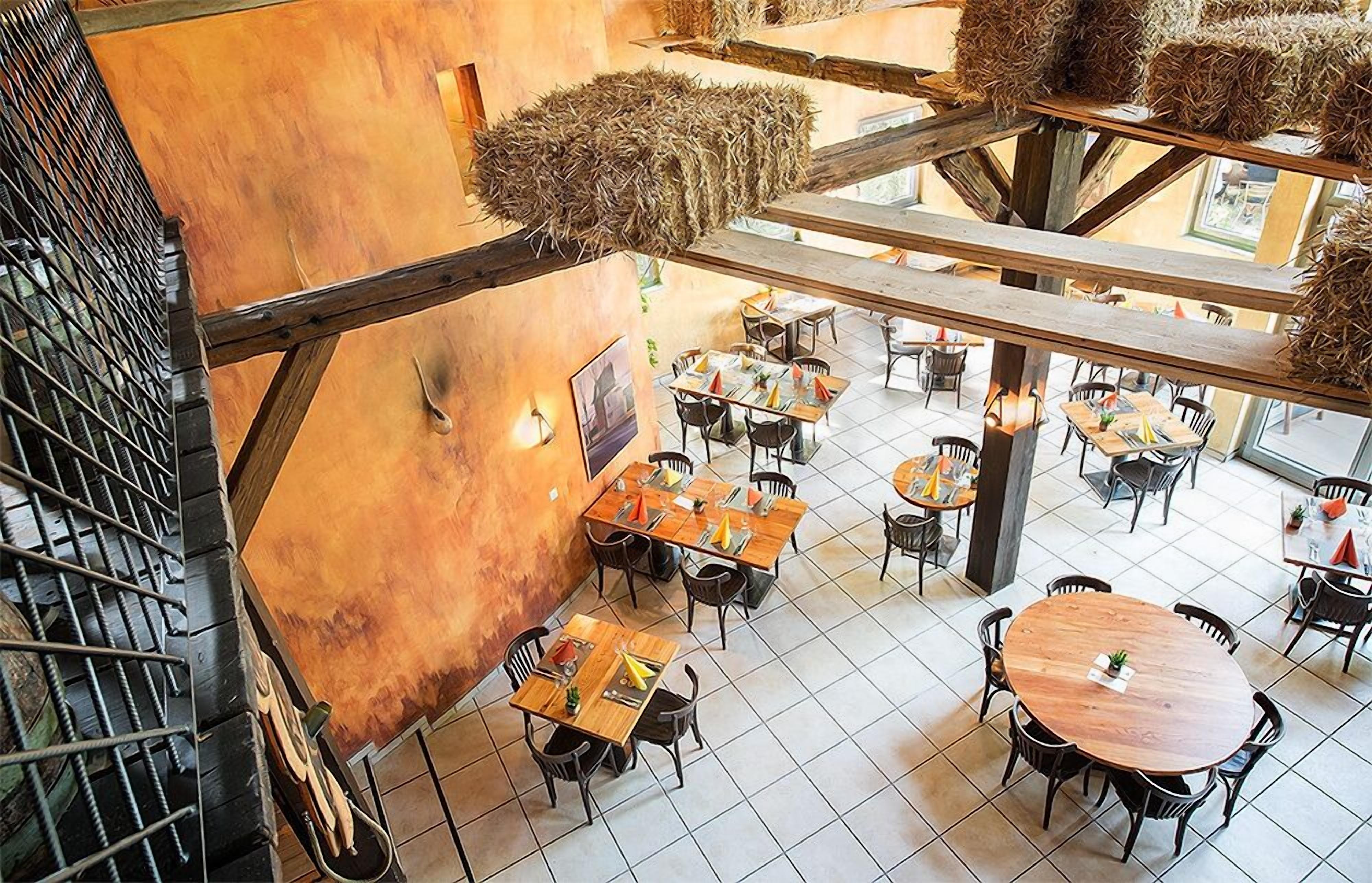 Un restaurante con varias mesas y sillas, una escalera decorada con heno y vistas al espacio exterior.