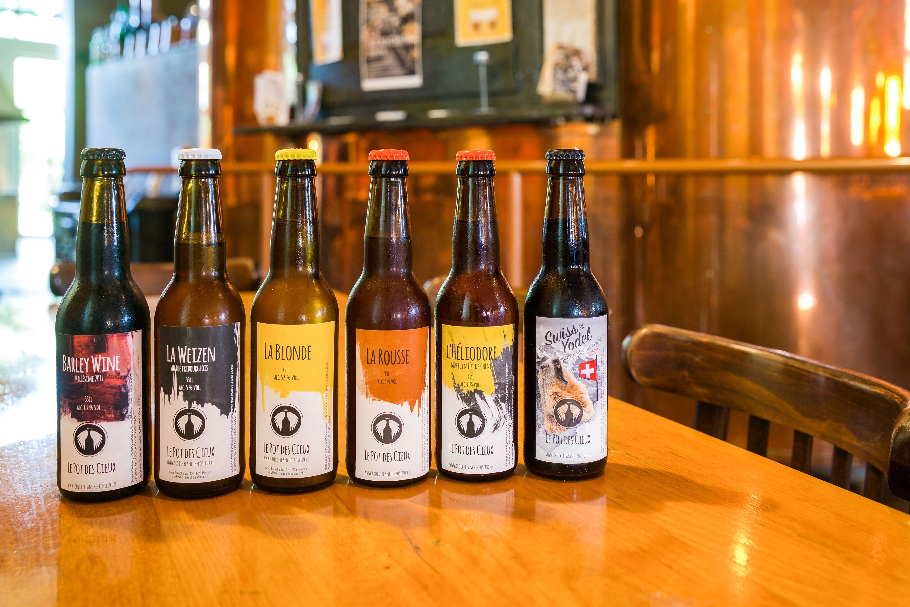 Six bottles of wine on a wooden table in a bar setting.
