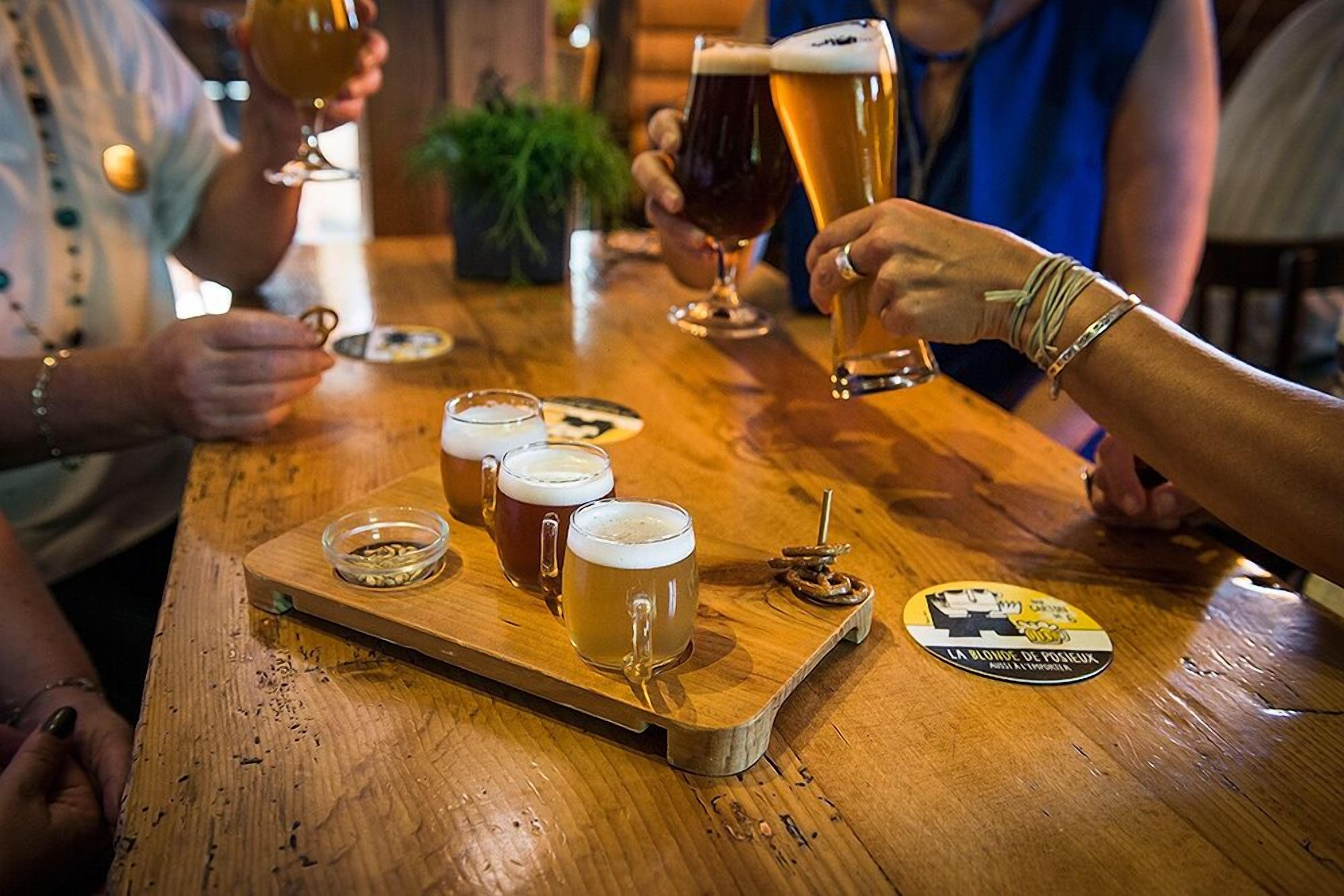 A wooden table with several glasses of beer and a coaster with text.