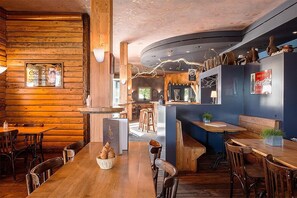 A cozy restaurant with wooden walls and a central bar area. - Hôtel-Résidence La Croix-Blanche (Hauterive)