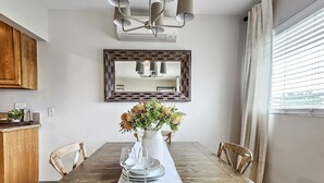 A dining area with a wooden table, chairs, a vase of flowers, and a chandelier. - Close to Beach &  Major Attractions. Outdoor Patio with Firepit.  Free Parking. (Culver City)