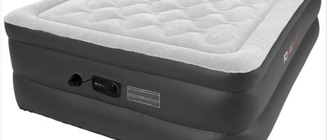 A black portable mattress with a quilted top and a power outlet on the side.
