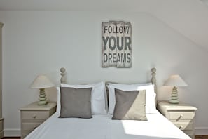 A bedroom with a bed, two bedside tables, and a wall-mounted sign.