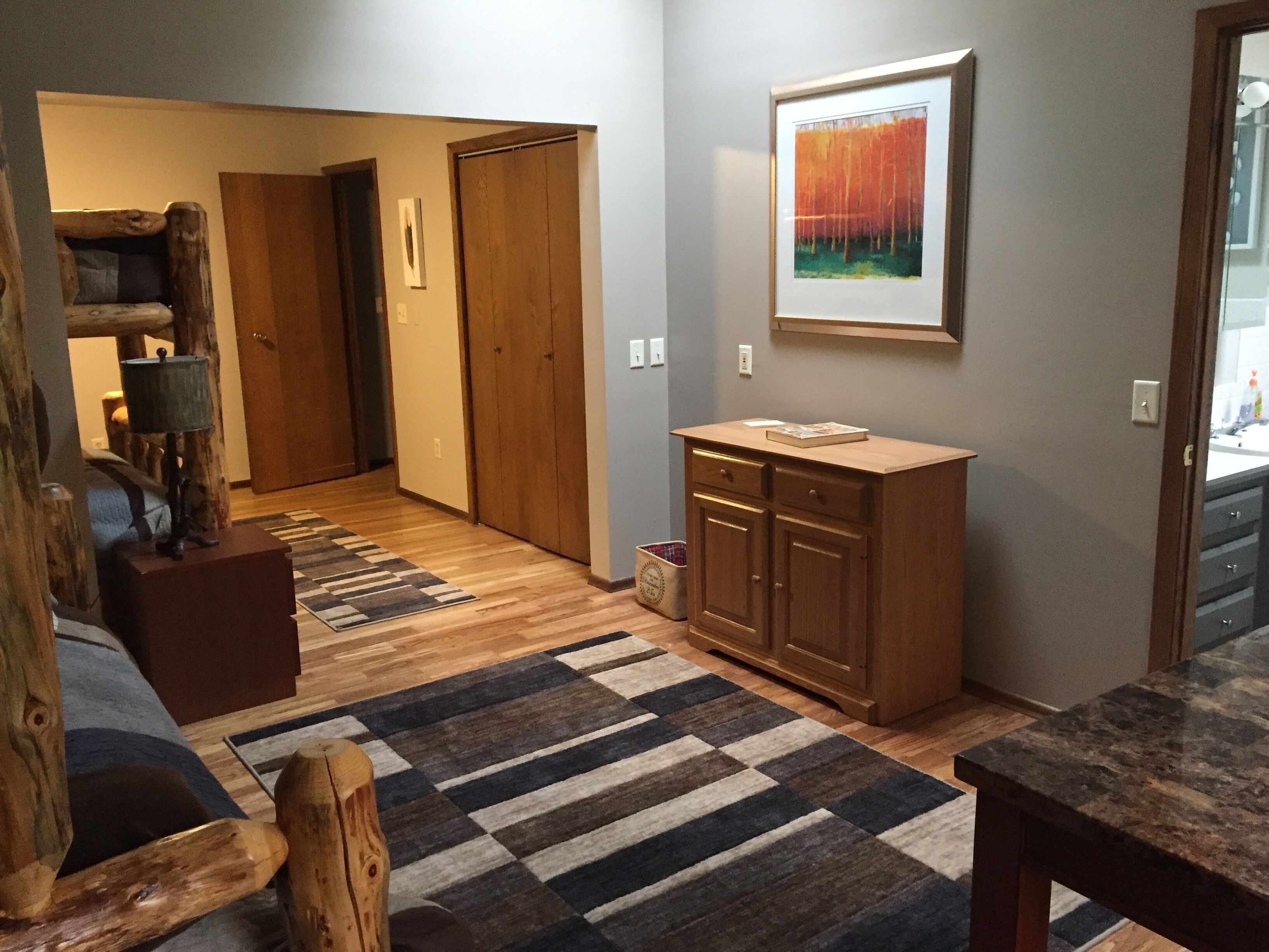 Un couloir avec un banc en bois, un tapis, une armoire et un tableau encadré accroché au mur.