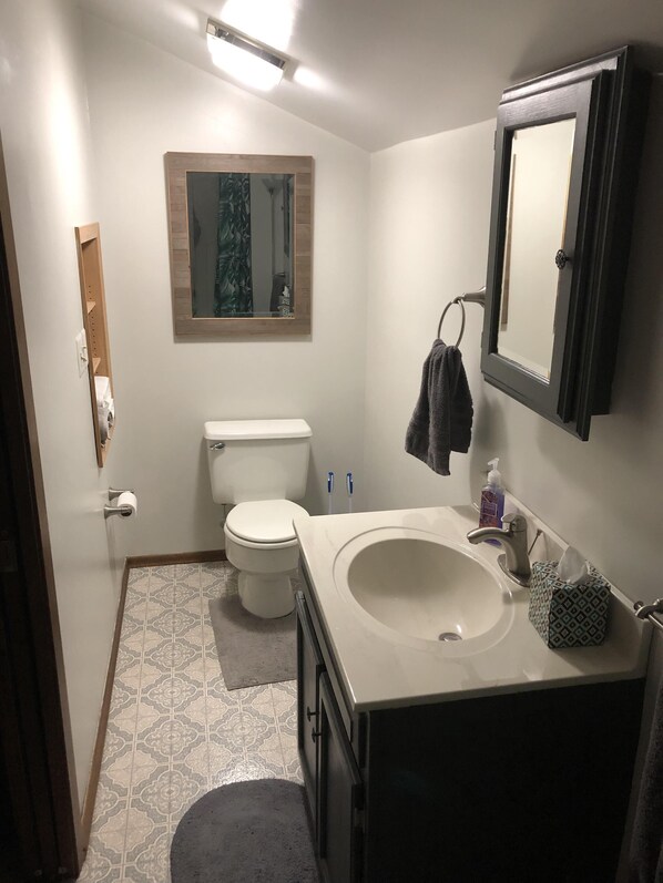 Un baño con inodoro, lavabo, espejo y una toalla colgada en la pared.