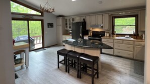 Una cocina moderna con una isla central, armarios blancos y un ventanal con vistas a zonas verdes.