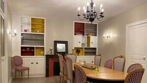 A dining room with a wooden table and chairs, a chandelier, and built-in shelves with various items.