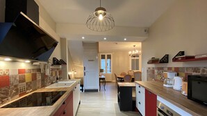 A modern kitchen with a central island, built-in appliances, and a dining area with a chandelier.