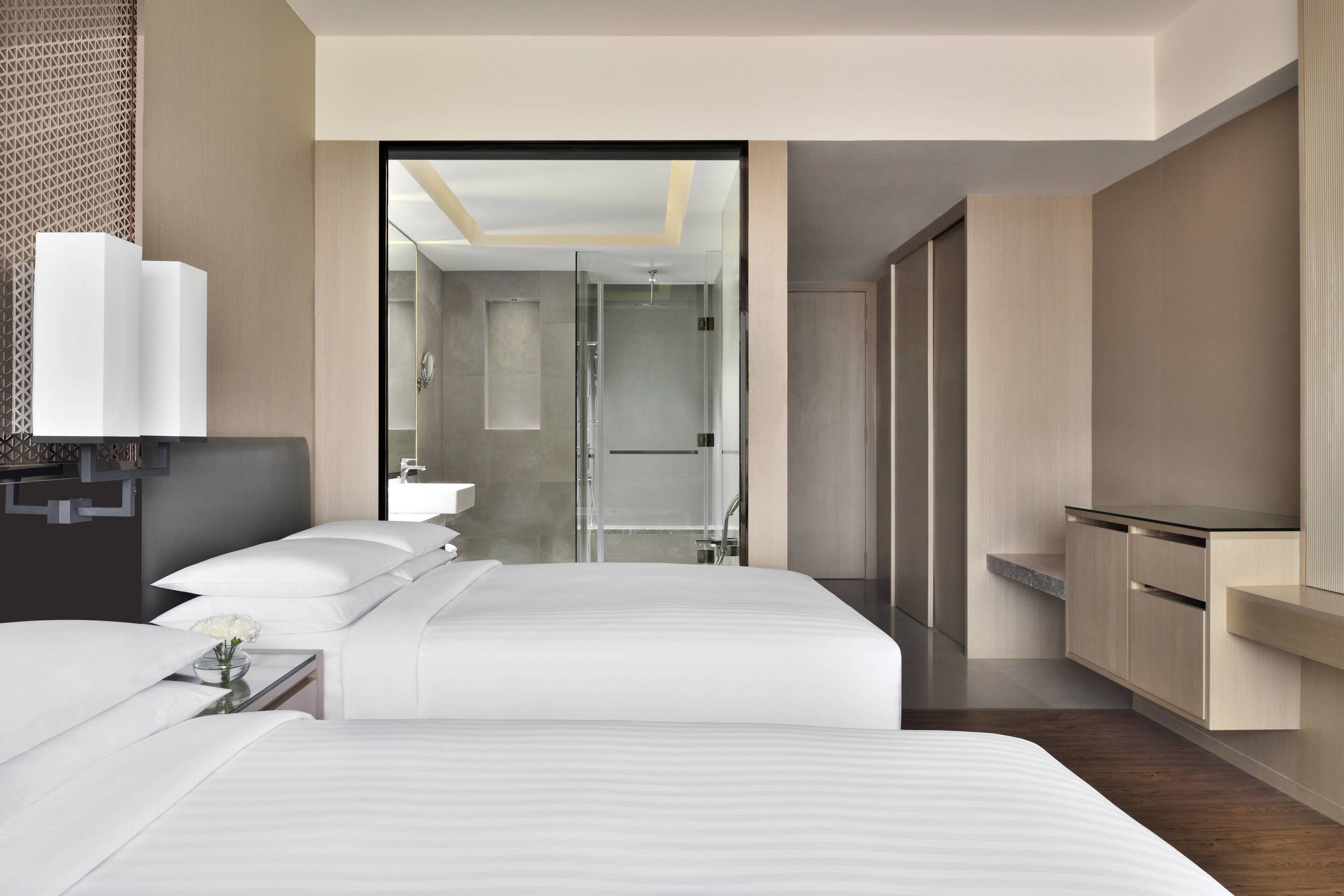 Habitación de hotel moderna con una cama grande, una mesita de noche, un espejo y vistas al baño.