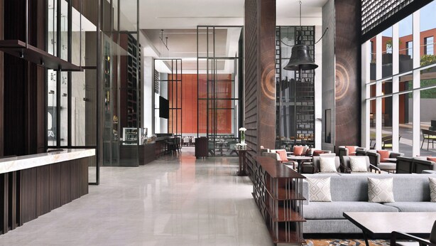 Un vestíbulo moderno con mostrador de recepción, zona de estar y amplias ventanas con vistas al exterior.
