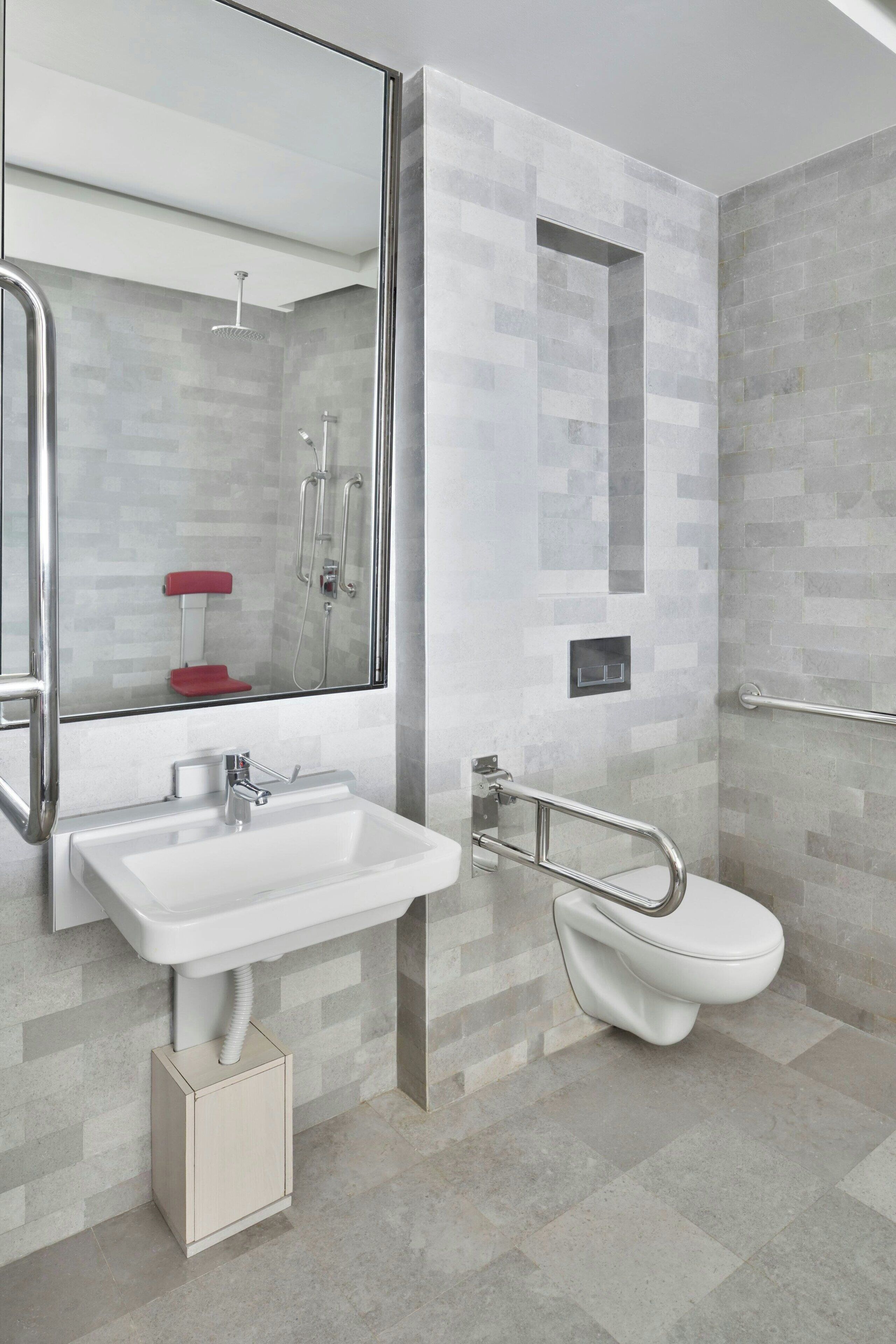 Een moderne badkamer met een wit wastafelmeubel, een douchecabine met glazen wanden en een wit toilet.