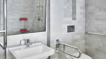 Een moderne badkamer met een wit wastafelmeubel, een douchecabine met glazen wanden en een wit toilet.
