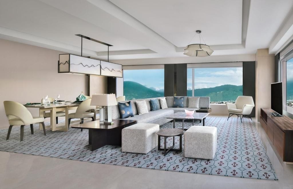 A modern living room with a large sofa, a dining table, and a TV.